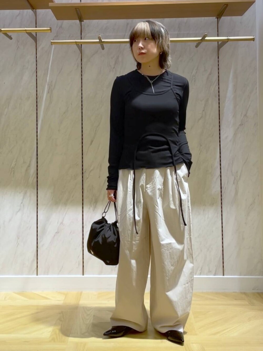 ブラック系のパンプス、ホワイト系のスラックス、ブラック系のショルダーバッグを着用したレディースの春コーディネートの5枚目の写真