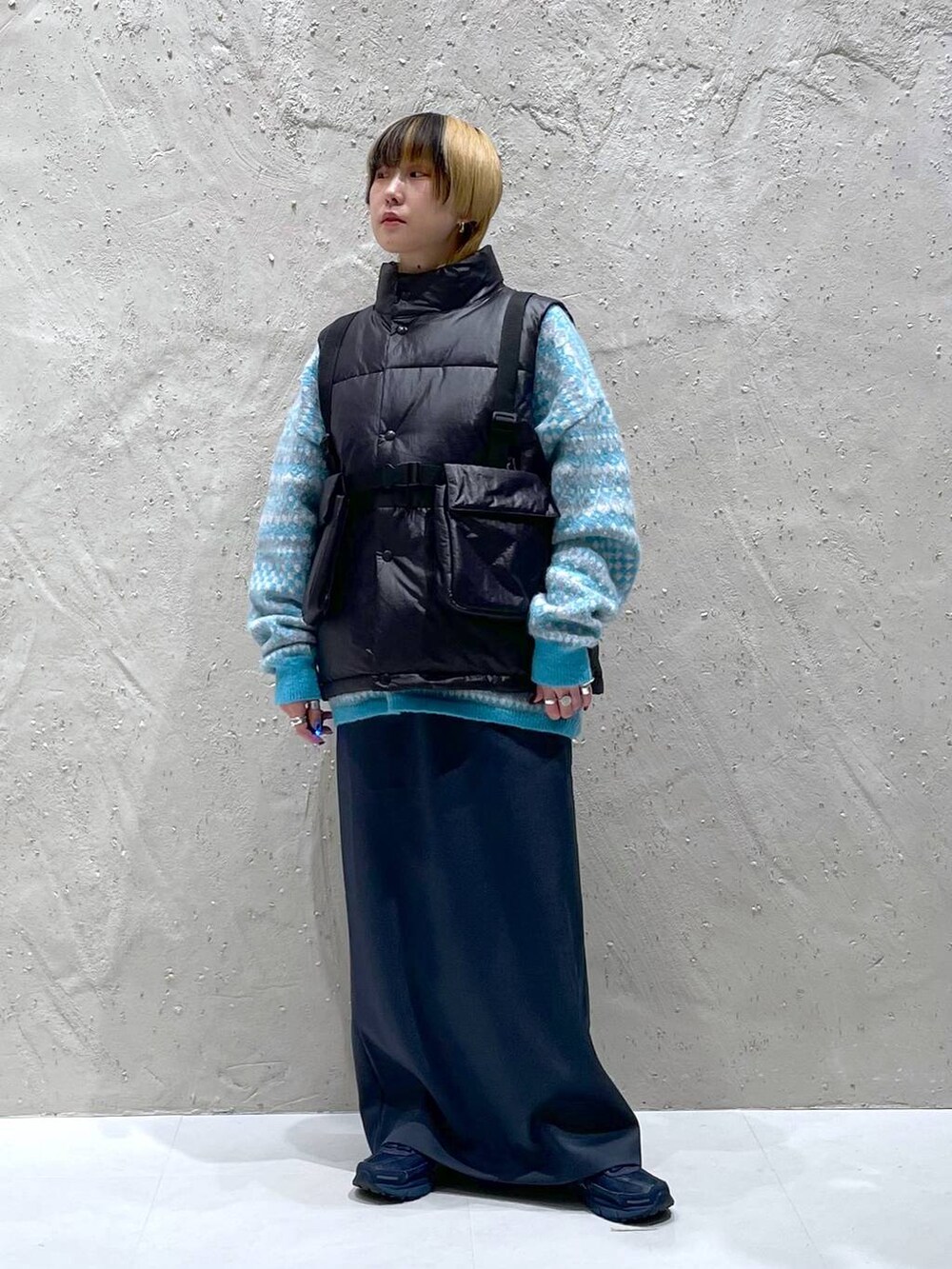 ブルー系のニット/セーター、グリーン系のスカート、ブラック系のダウンベストを着用したレディースの秋コーディネートの6枚目の写真