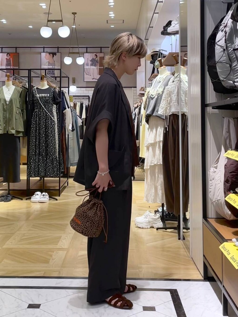 グレー系のテーラードジャケット、グレー系のスラックス、ブラウン系のサンダルを着用したレディースの夏コーディネートの4枚目の写真