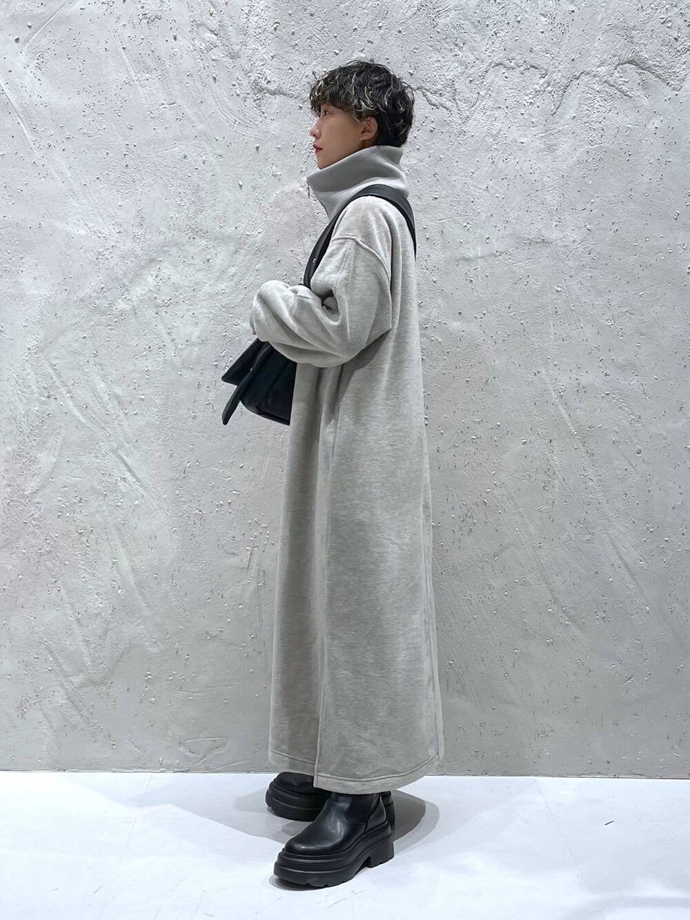 ブラック系のブーツ、グレー系のワンピース、ブラック系のショルダーバッグを着用したレディースの秋コーディネートの2枚目の写真