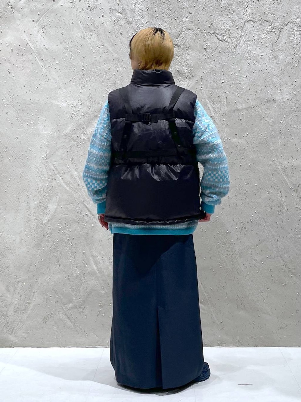 ブルー系のニット/セーター、グリーン系のスカート、ブラック系のダウンベストを着用したレディースの秋コーディネートの3枚目の写真