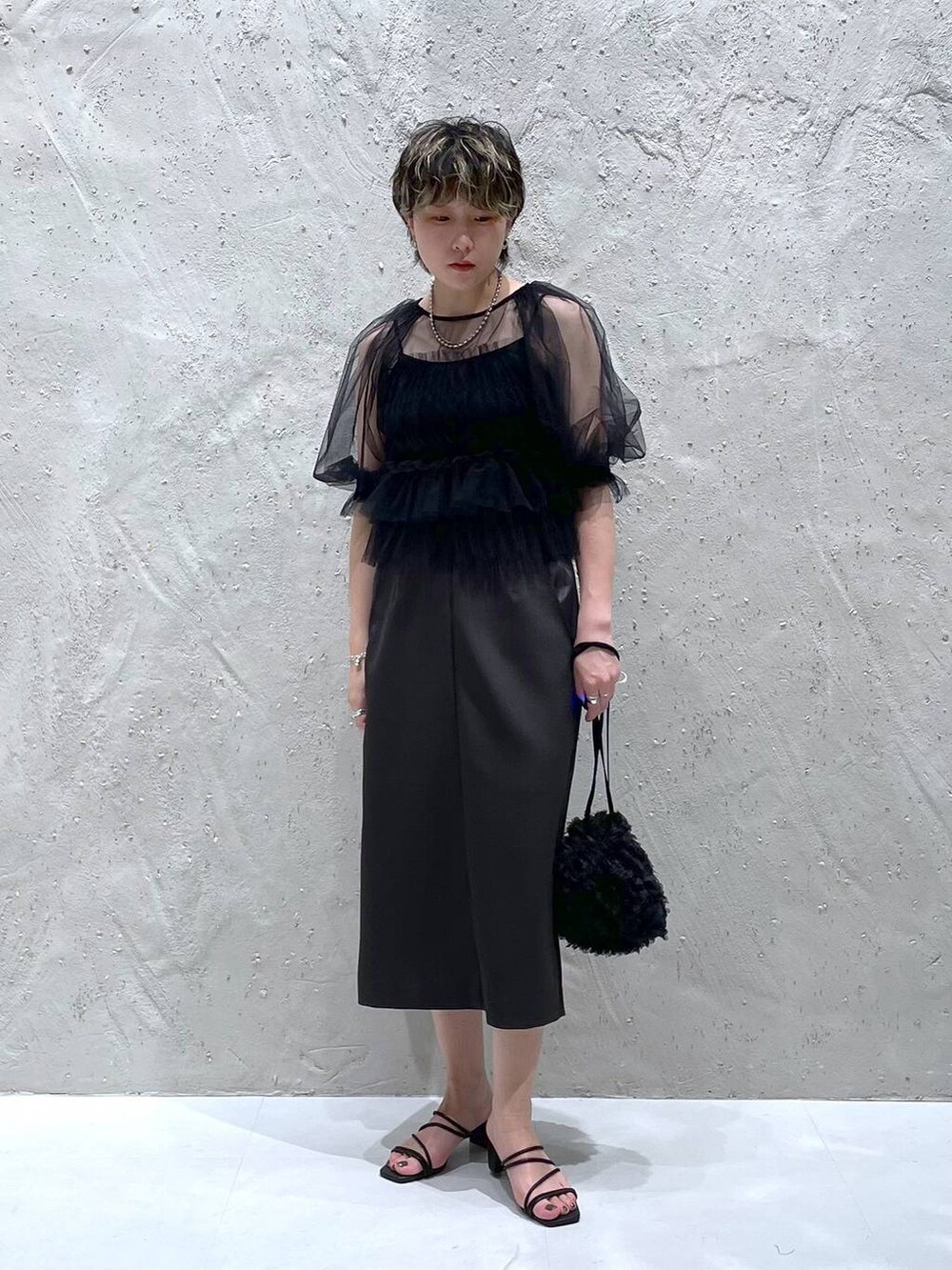 グレー系のスカート、ブラック系のサンダル、ブラック系のハンドバッグを着用したレディースの夏コーディネートの5枚目の写真