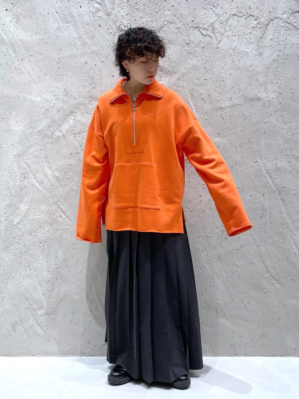 オレンジ系のスウェット、グレー系のスカート、ブラック系のブーツを着用したレディースの冬コーディネートの3枚目の写真