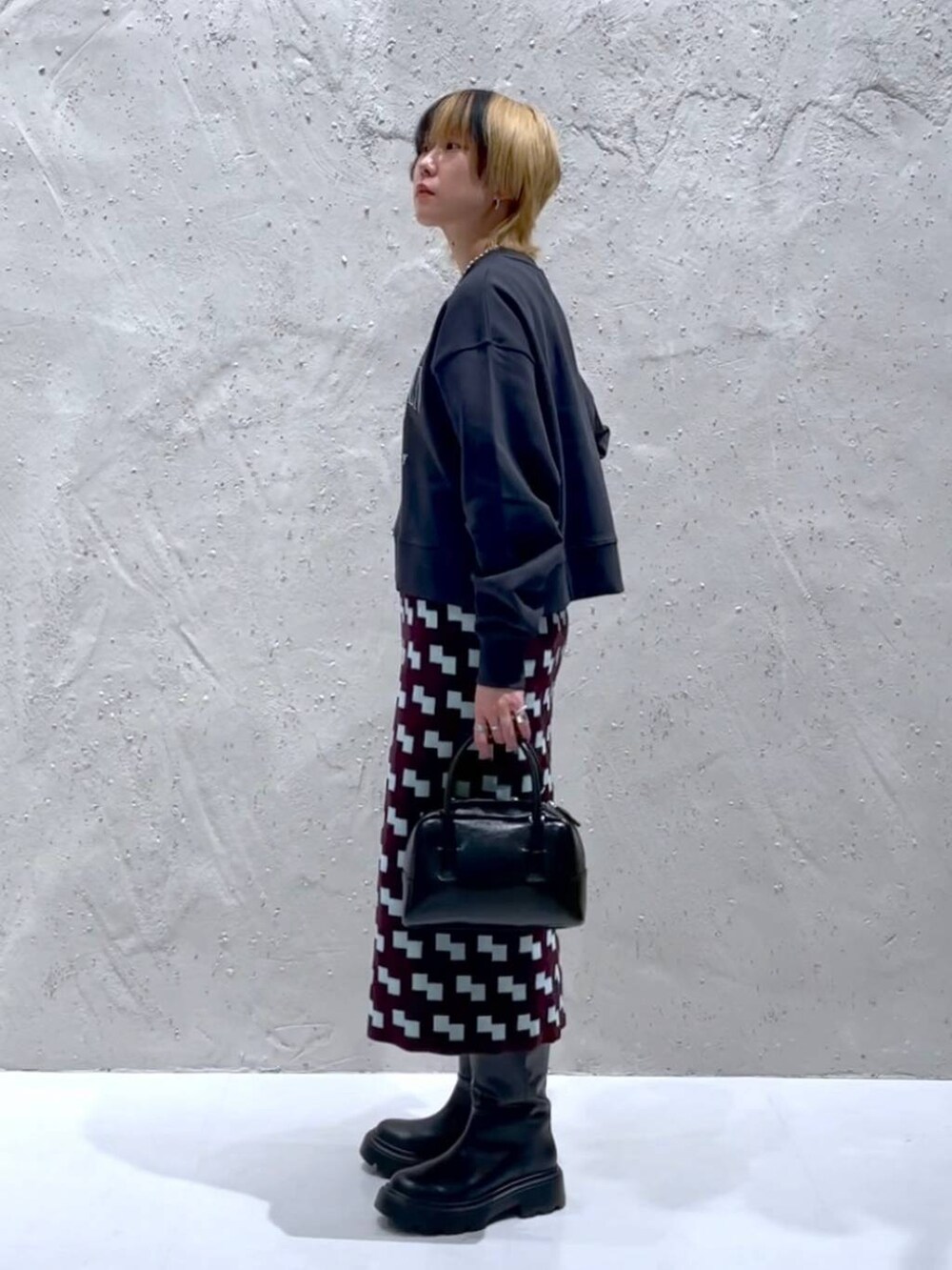 グレー系のスウェット、ブラック系のボストンバッグ、ブラウン系のスカートを着用したレディースの秋コーディネートの2枚目の写真