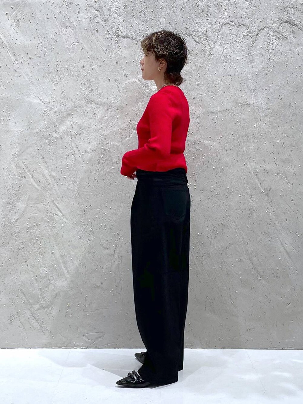 ブラック系のパンプス、レッド系のニット/セーター、ブラック系のデニムパンツを着用したレディースの秋コーディネートの2枚目の写真