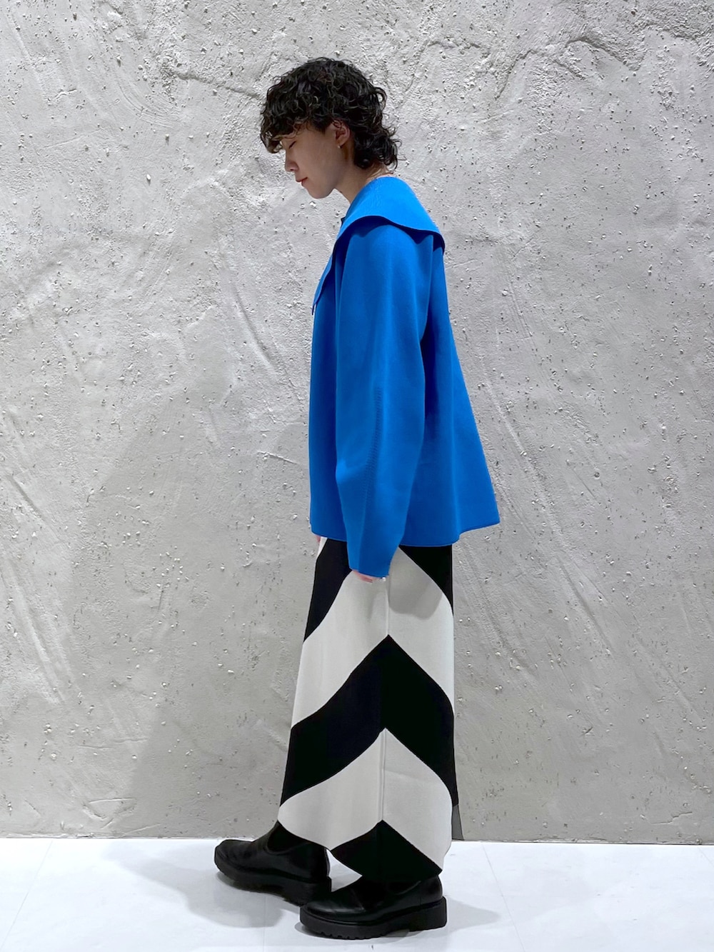 ブルー系のニット/セーター、ブラック系のスカート、ブラック系のブーツを着用したレディースの冬コーディネートの2枚目の写真