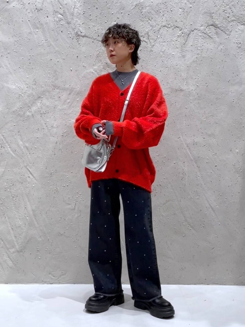 ブラック系のブーツ、シルバー系のボストンバッグ、オレンジ系のニット/セーターを着用したレディースの冬コーディネートの5枚目の写真