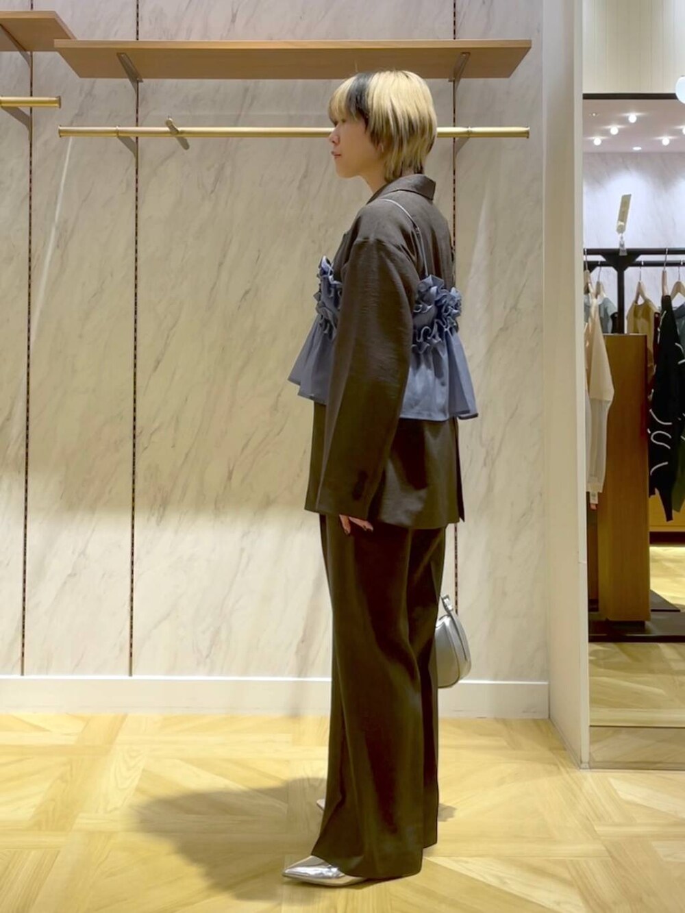 グレー系のスラックス、グレー系のテーラードジャケット、シルバー系のトートバッグを着用したレディースの春コーディネートの2枚目の写真