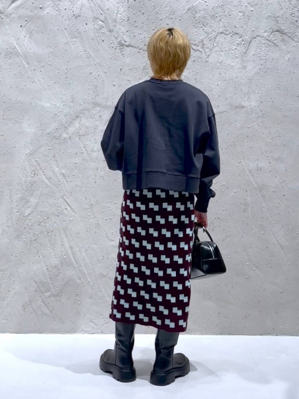 グレー系のスウェット、ブラック系のボストンバッグ、ブラウン系のスカートを着用したレディースの秋コーディネートの3枚目の写真