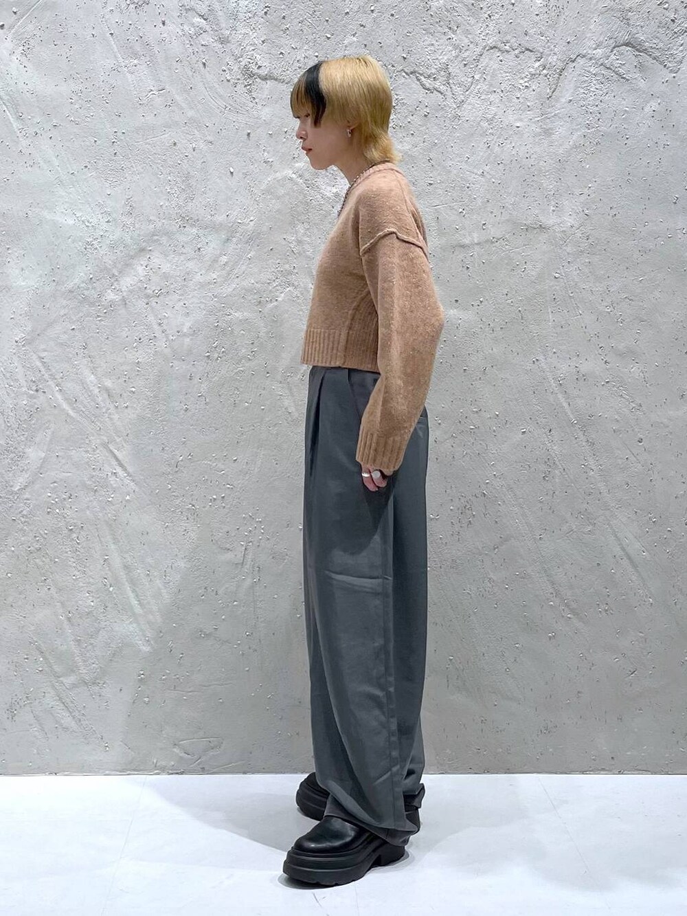 オレンジ系のニット/セーター、グレー系のその他パンツを着用したレディースの秋コーディネートの4枚目の写真