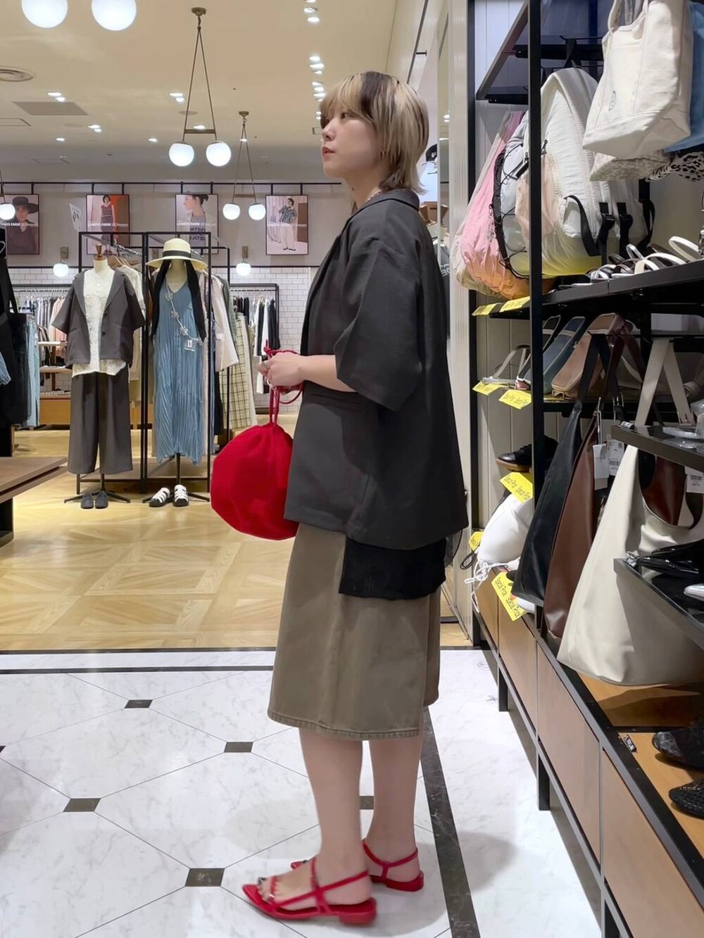 グレー系のテーラードジャケット、レッド系のサンダル、ブラウン系のデニムパンツを着用したレディースの春コーディネートの2枚目の写真