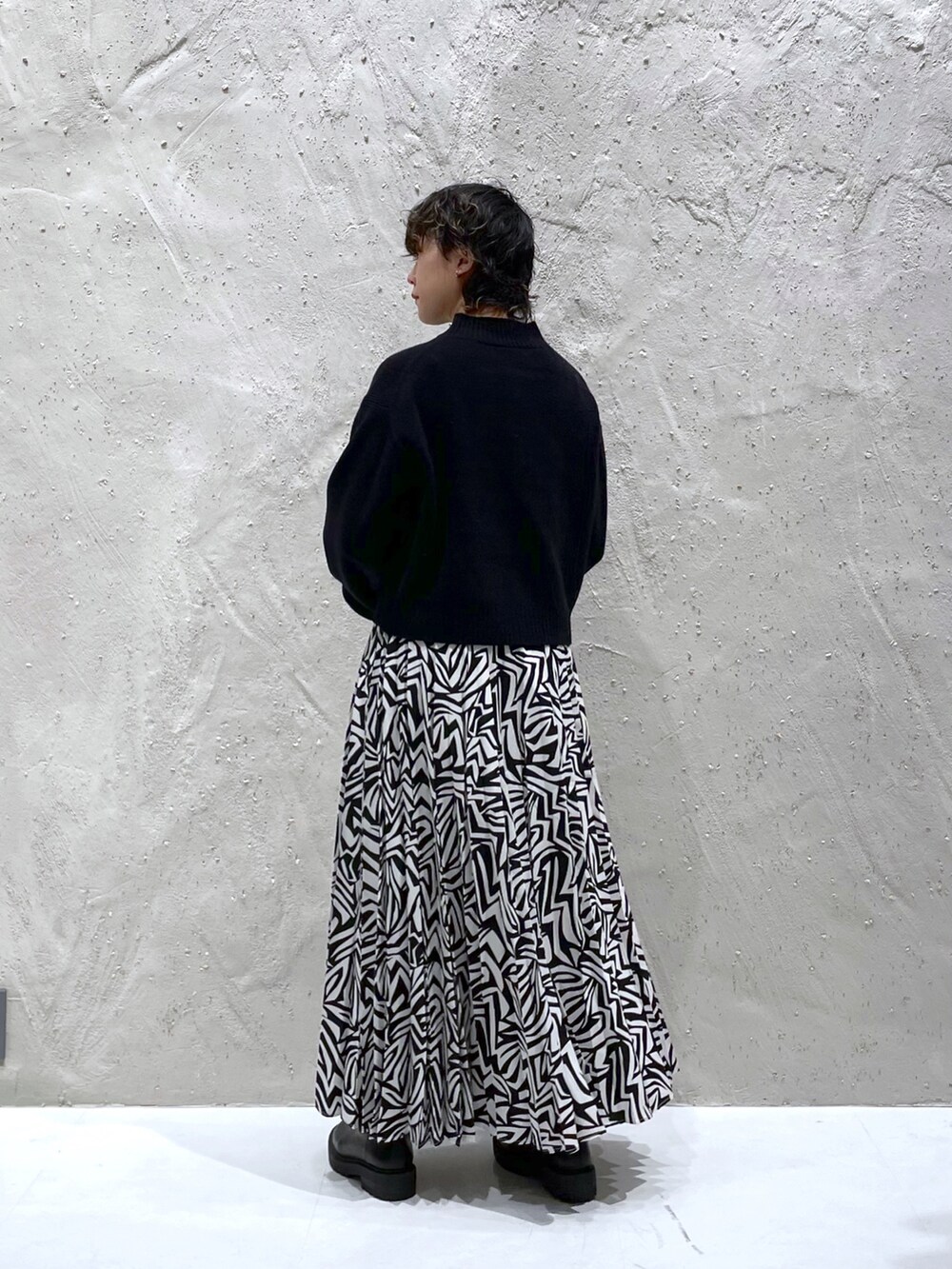 ブラック系のワンピース、ブラック系のスカート、ブラック系のブーツを着用したレディースの冬コーディネートの4枚目の写真