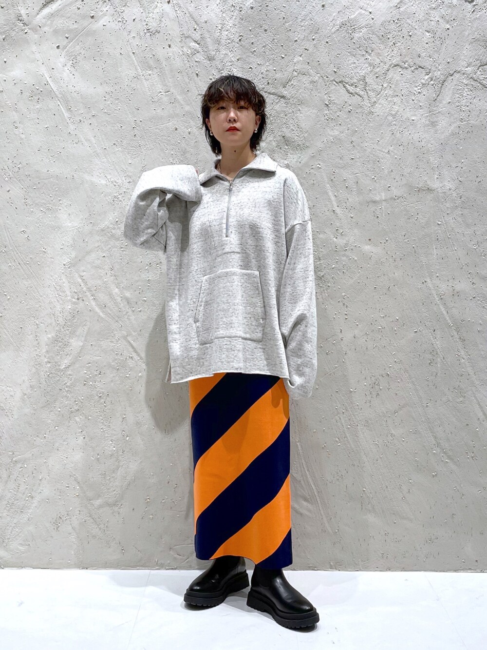 ホワイト系のスウェット、ブルー系のスカート、ブラック系のブーツを着用したレディースの冬コーディネートの2枚目の写真