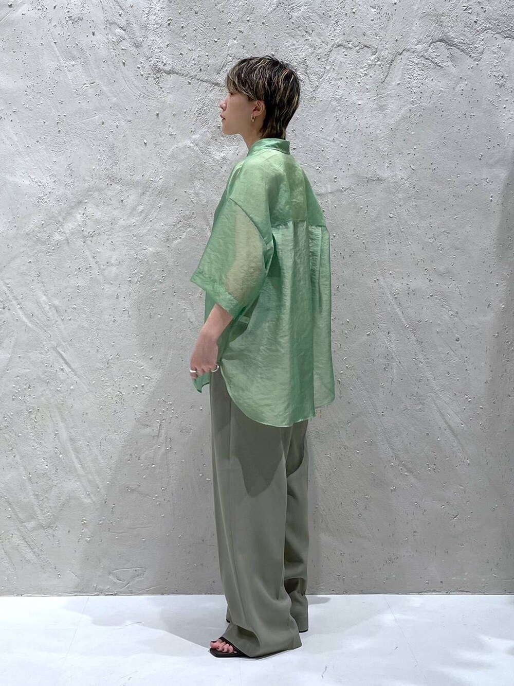 グリーン系のスラックス、グリーン系のシャツ/ブラウス、ブラック系のサンダルを着用したレディースの夏コーディネートの2枚目の写真