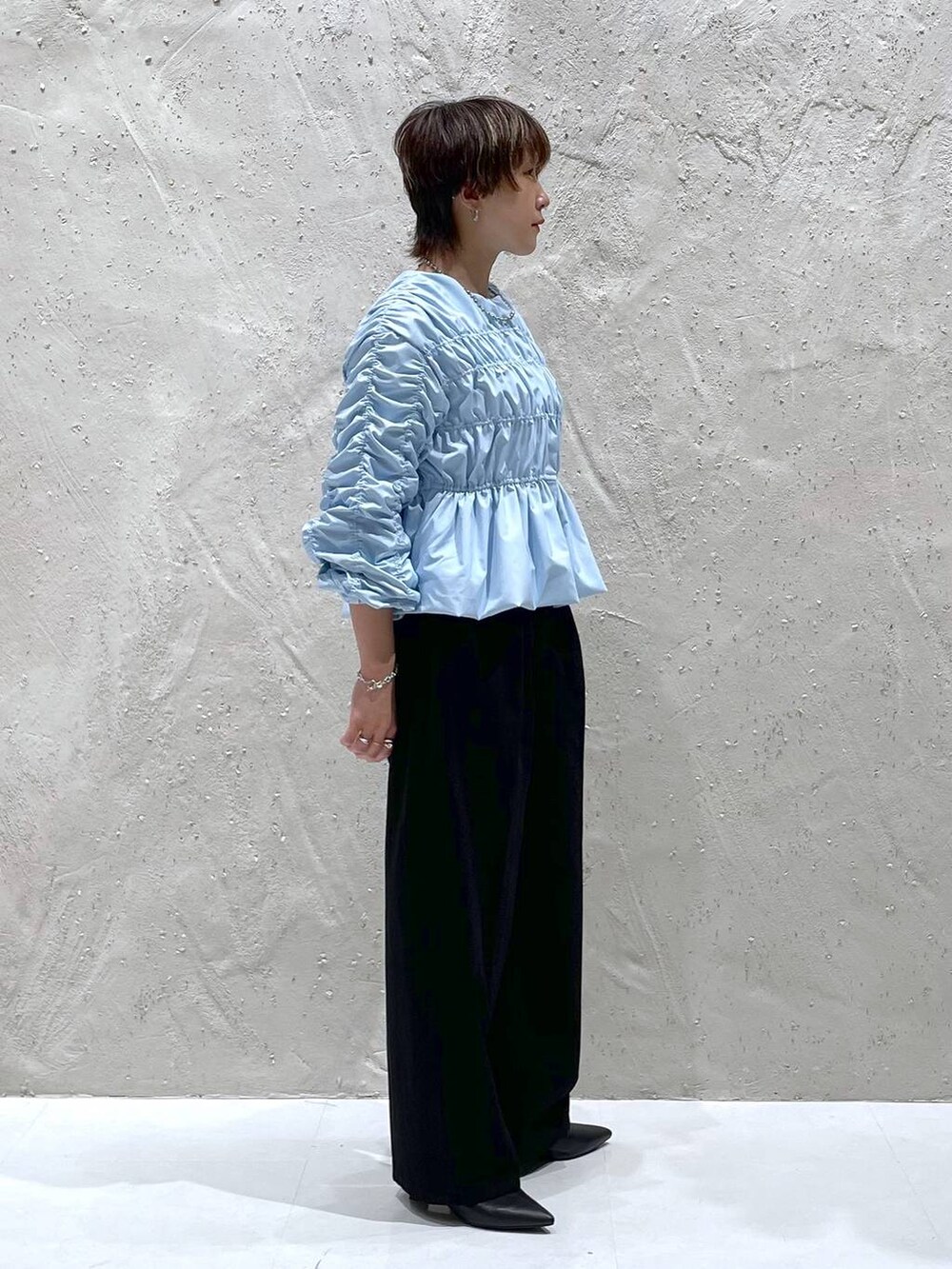 ブラック系のブーツ、ブラック系のデニムパンツ、ブルー系のシャツ/ブラウスを着用したレディースの秋コーディネートの2枚目の写真