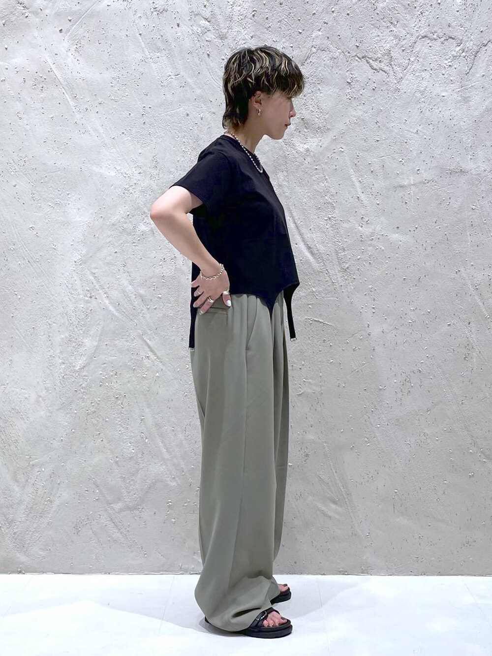 グリーン系のスラックス、ブラック系のTシャツ/カットソー、ブラック系のサンダルを着用したレディースの夏コーディネートの2枚目の写真