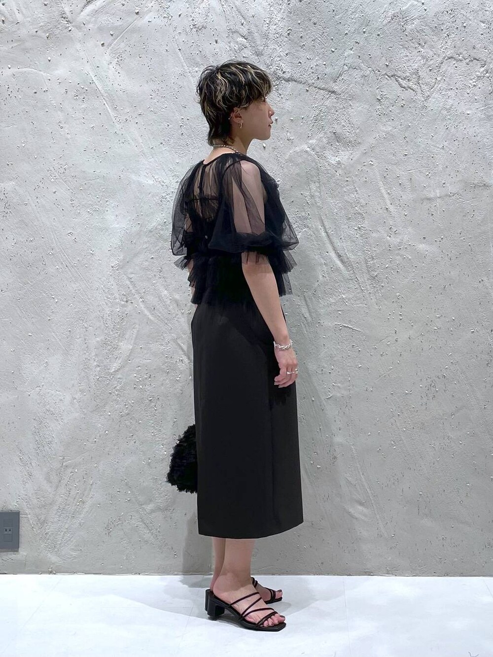 グレー系のスカート、ブラック系のサンダル、ブラック系のハンドバッグを着用したレディースの夏コーディネートの4枚目の写真