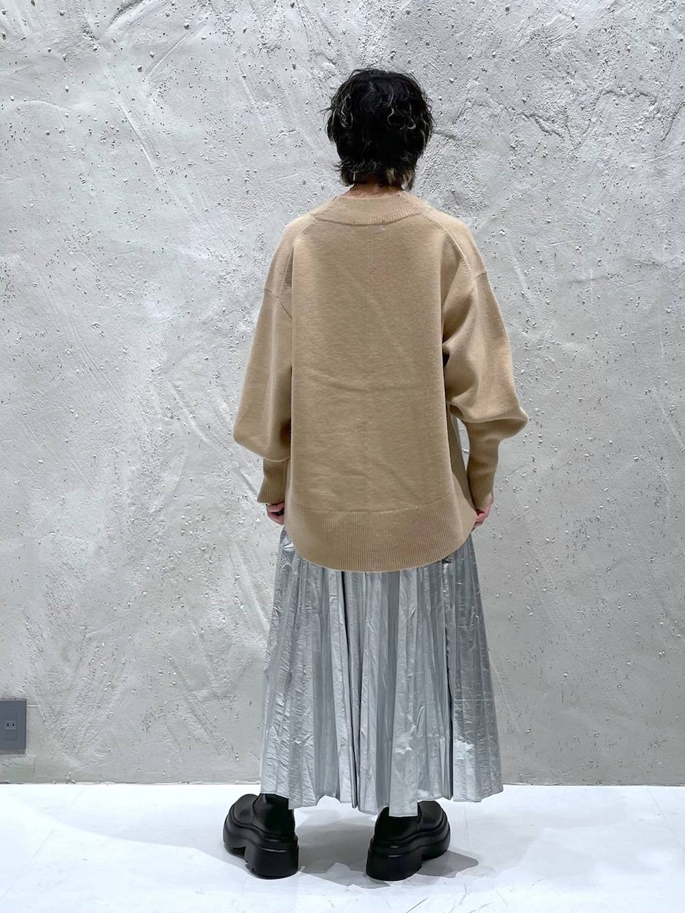 ブラック系のブーツ、ベージュ系のニット/セーター、シルバー系のスカートを着用したレディースの秋コーディネートの3枚目の写真