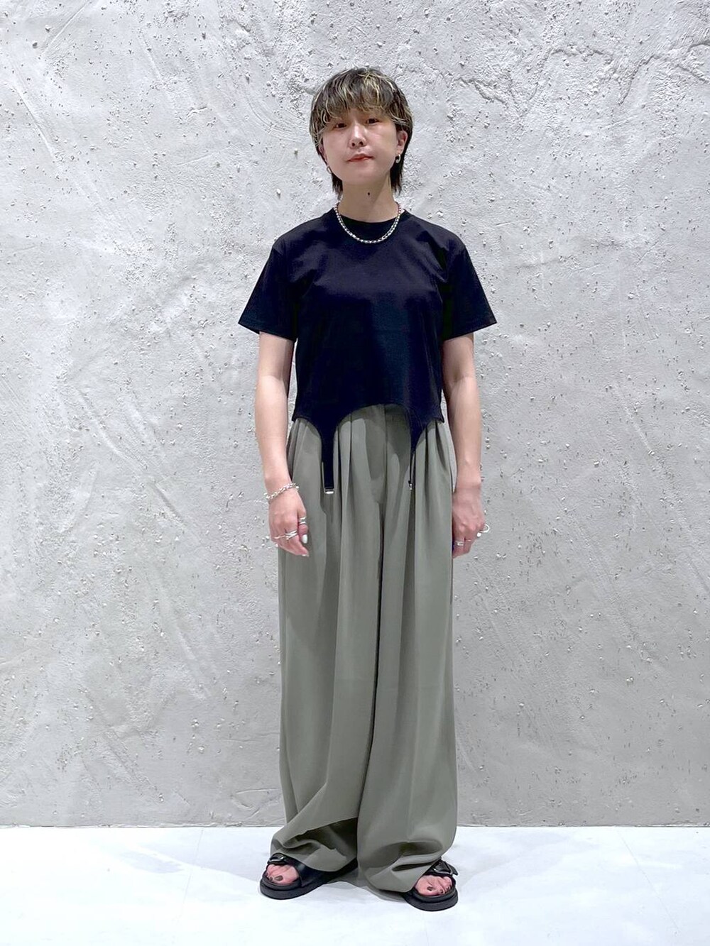 グリーン系のスラックス、ブラック系のTシャツ/カットソー、ブラック系のサンダルを着用したレディースの夏コーディネートの6枚目の写真