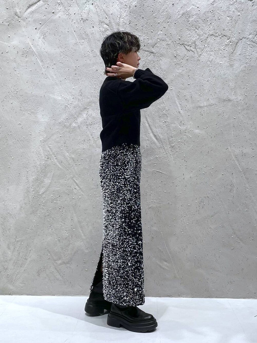 ブラック系のブーツ、ブラック系のニット/セーター、シルバー系のスカートを着用したレディースの秋コーディネートの2枚目の写真