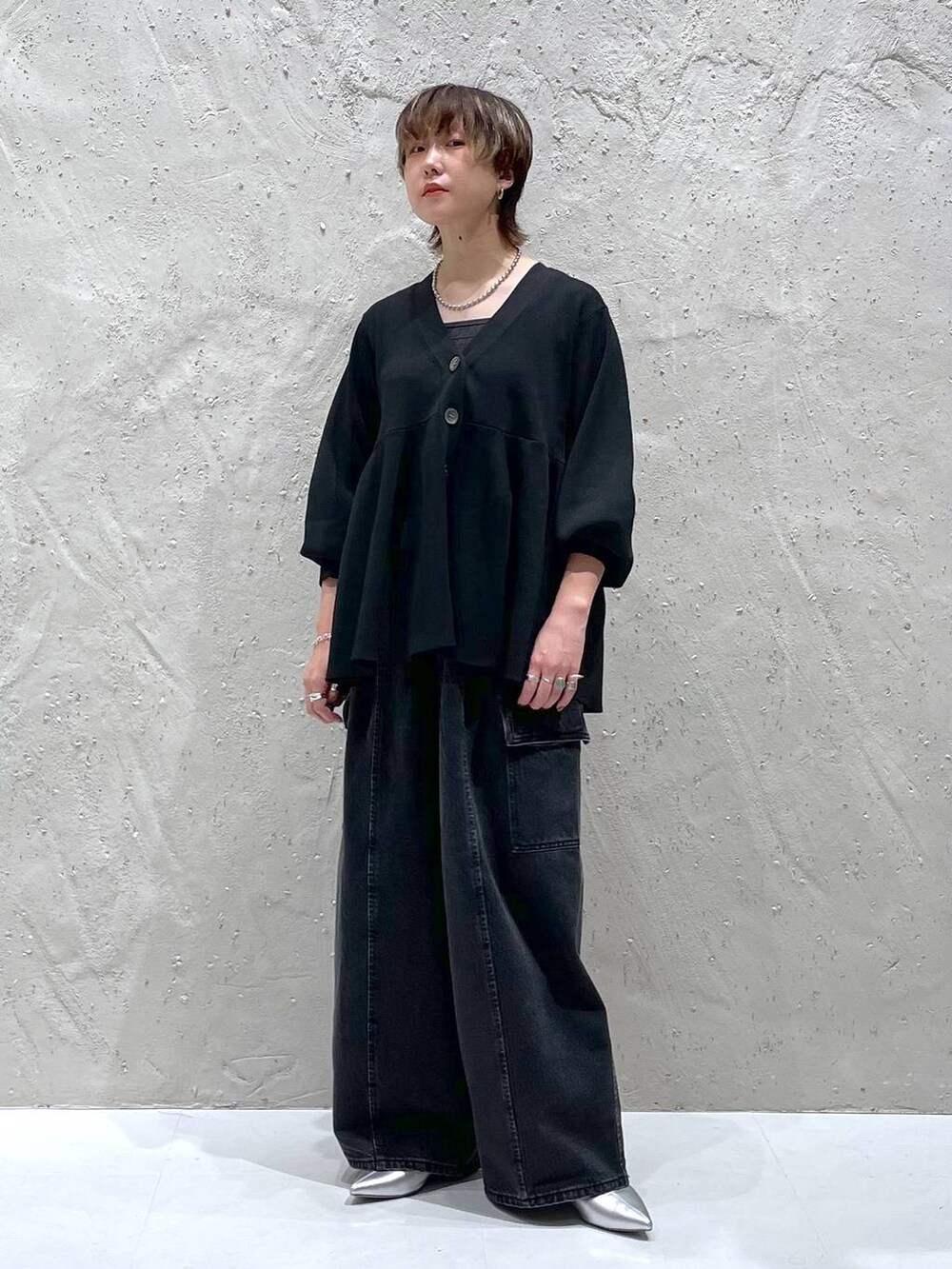 ブラック系のデニムパンツ、ブラック系のカーディガン/ボレロ、シルバー系のブーツを着用したレディースの秋コーディネートの4枚目の写真