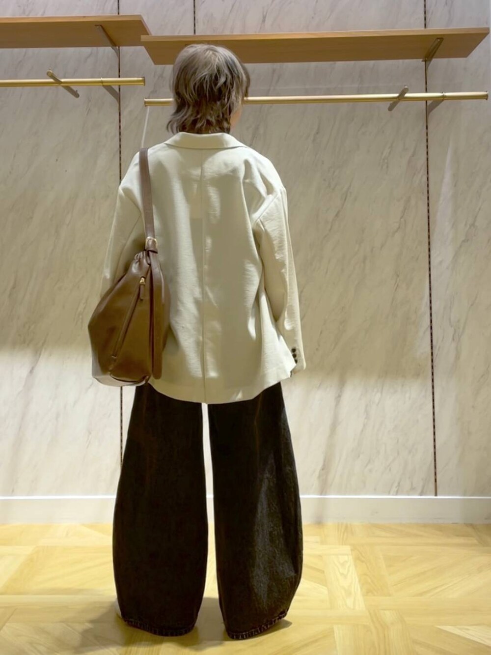 ブラウン系のショルダーバッグ、ホワイト系のテーラードジャケット、ブラック系のデニムパンツを着用したレディースの春コーディネートの3枚目の写真