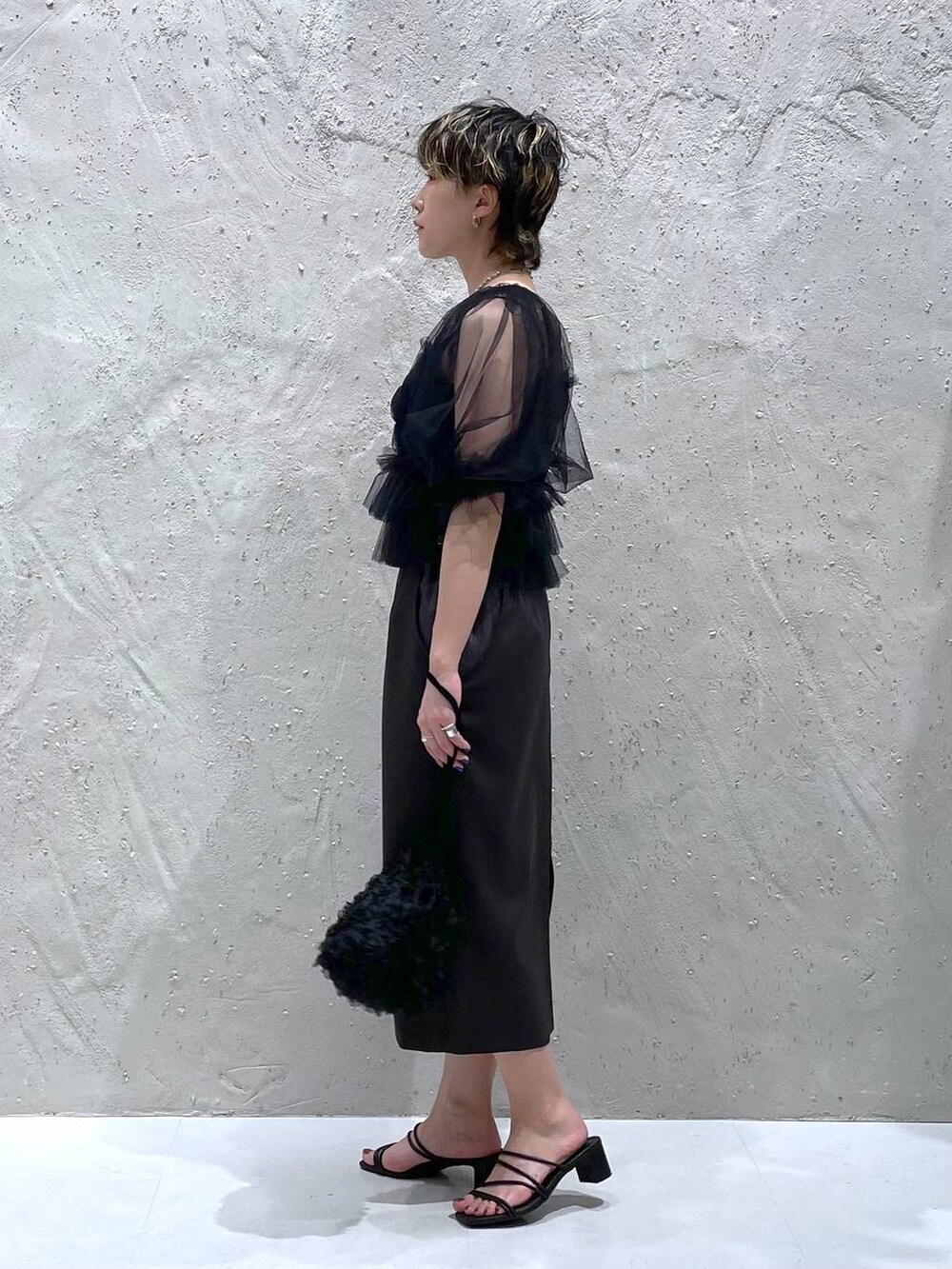 グレー系のスカート、ブラック系のサンダル、ブラック系のハンドバッグを着用したレディースの夏コーディネートの2枚目の写真