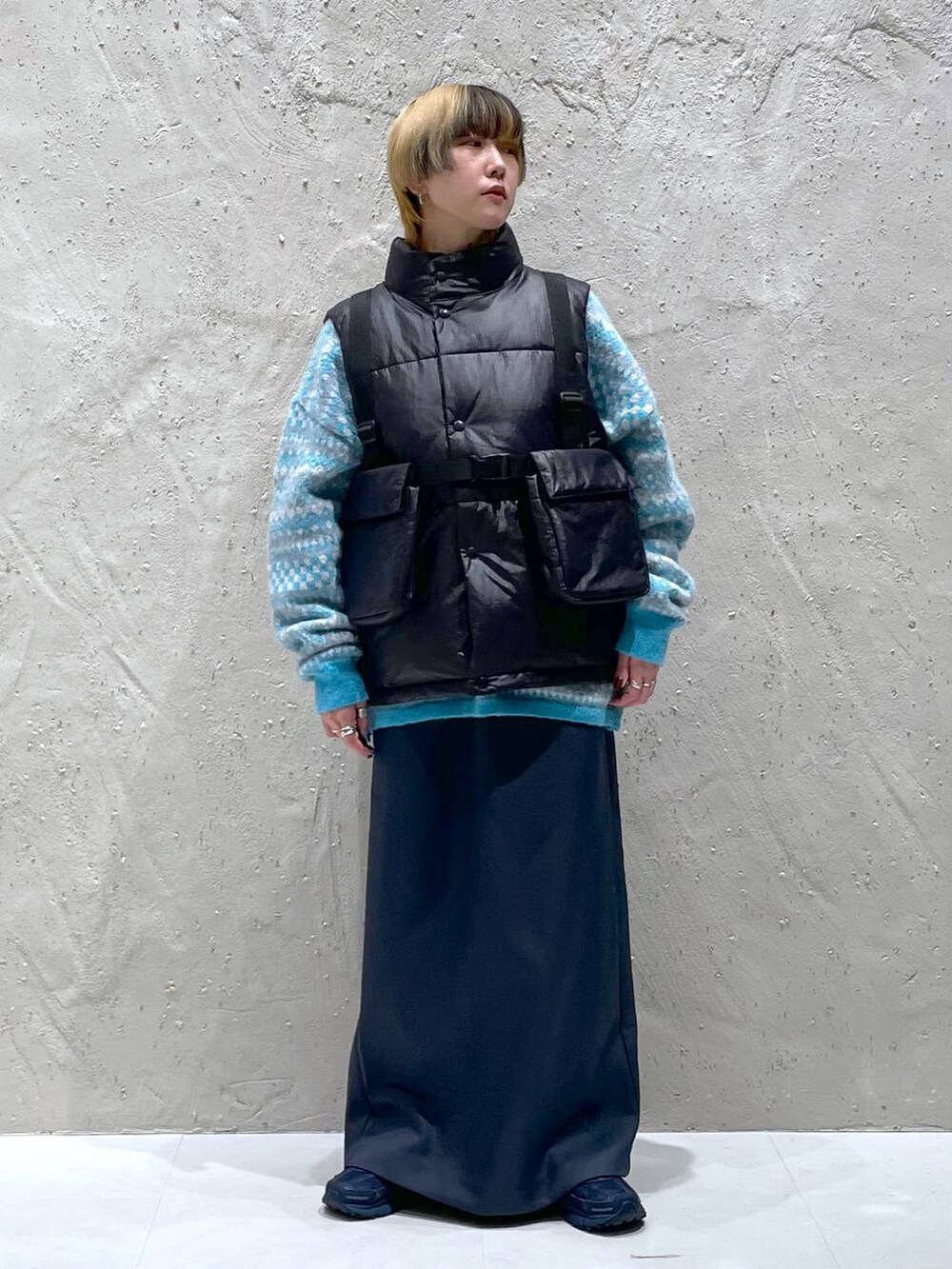 ブルー系のニット/セーター、グリーン系のスカート、ブラック系のダウンベストを着用したレディースの秋コーディネートの5枚目の写真