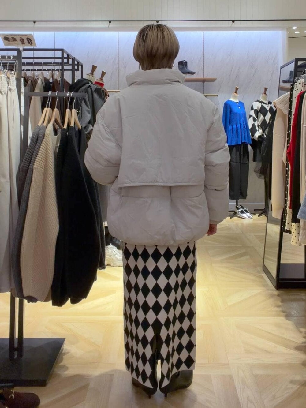 イエロー系のニット/セーター、グレー系のダウンジャケット/コート、その他のスカートを着用したレディースの秋コーディネートの3枚目の写真