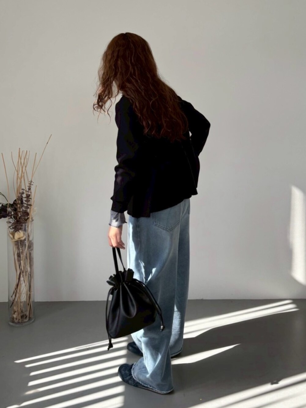 ブラック系のニット/セーター、ブルー系のデニムパンツ、ブルー系のスニーカーを着用したレディースの冬コーディネートの3枚目の写真