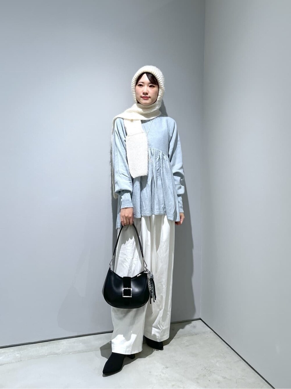 ブルー系のニット/セーター、ホワイト系のその他パンツ、ブラック系のショルダーバッグを着用したレディースの冬コーディネートの2枚目の写真