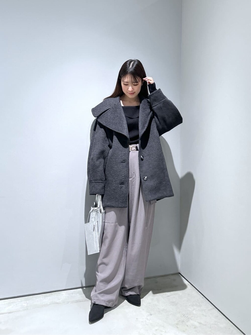 グレー系のチェスターコート、ブラック系のニット/セーター、グレー系のその他パンツを着用したレディースの冬コーディネートの4枚目の写真