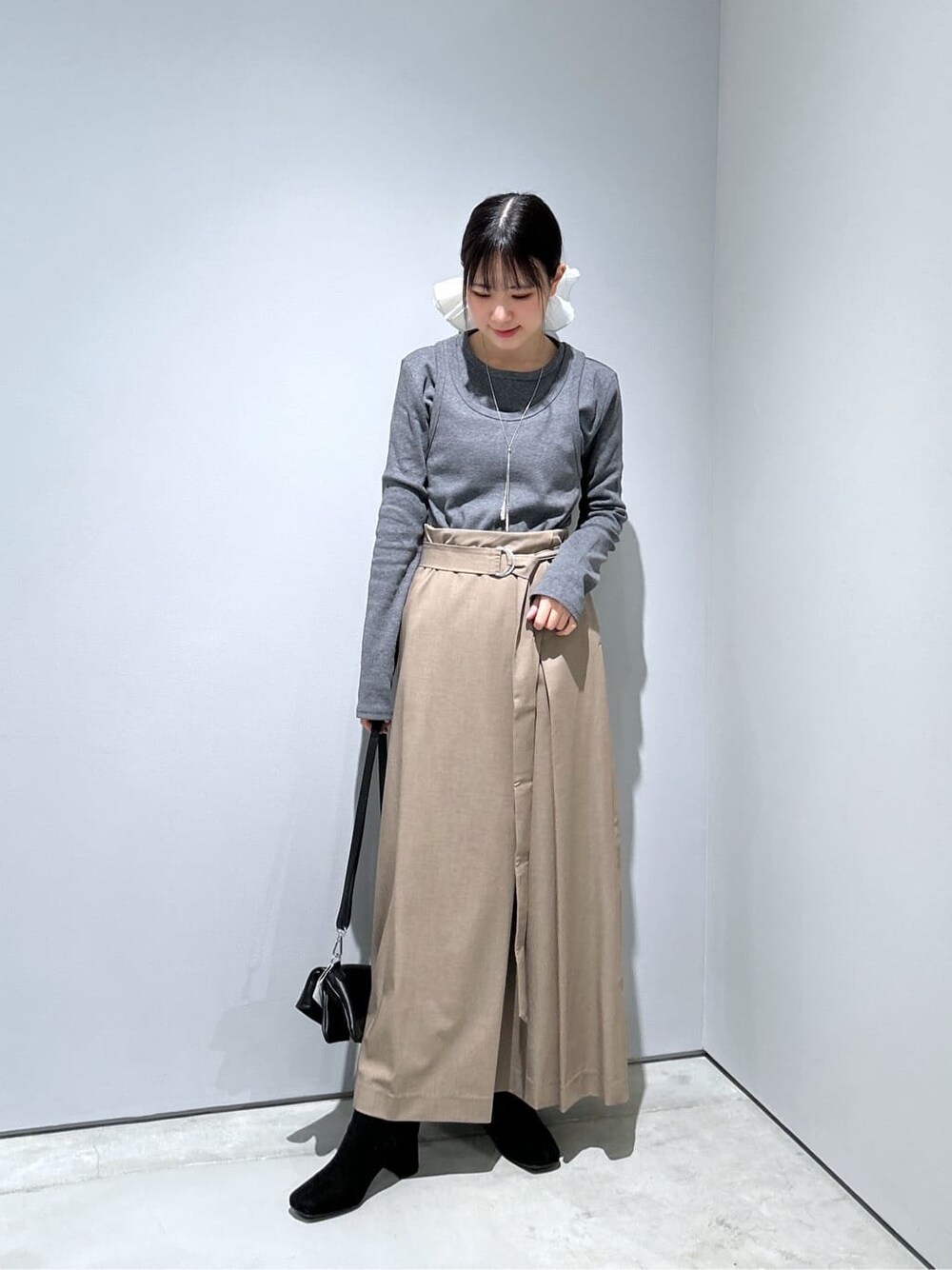 グレー系のTシャツ/カットソー、ベージュ系のスカート、ブラック系のショルダーバッグを着用したレディースの冬コーディネートの4枚目の写真