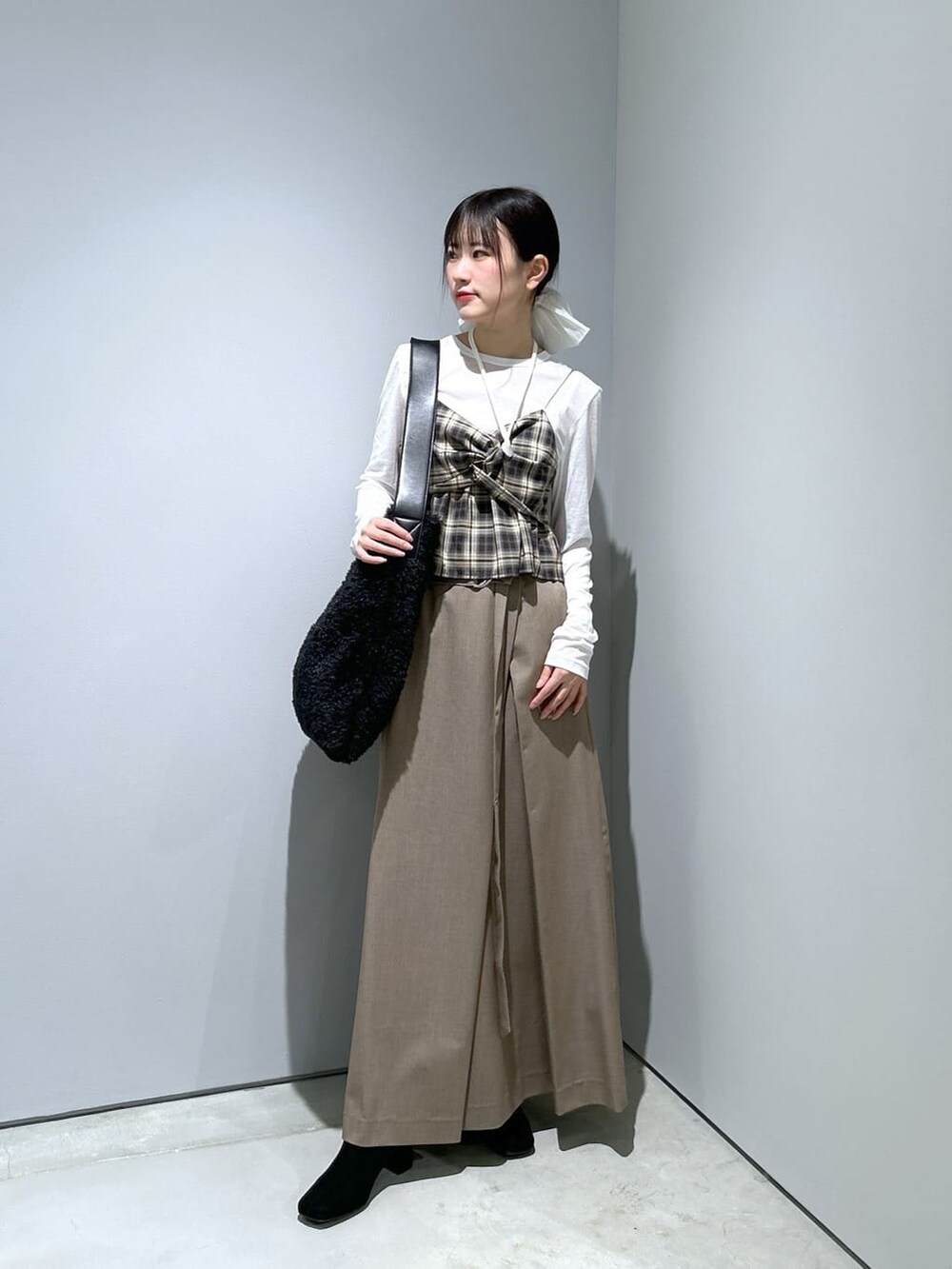 ベージュ系のタンクトップ、ホワイト系のTシャツ/カットソー、ベージュ系のスカートを着用したレディースの冬コーディネートの3枚目の写真