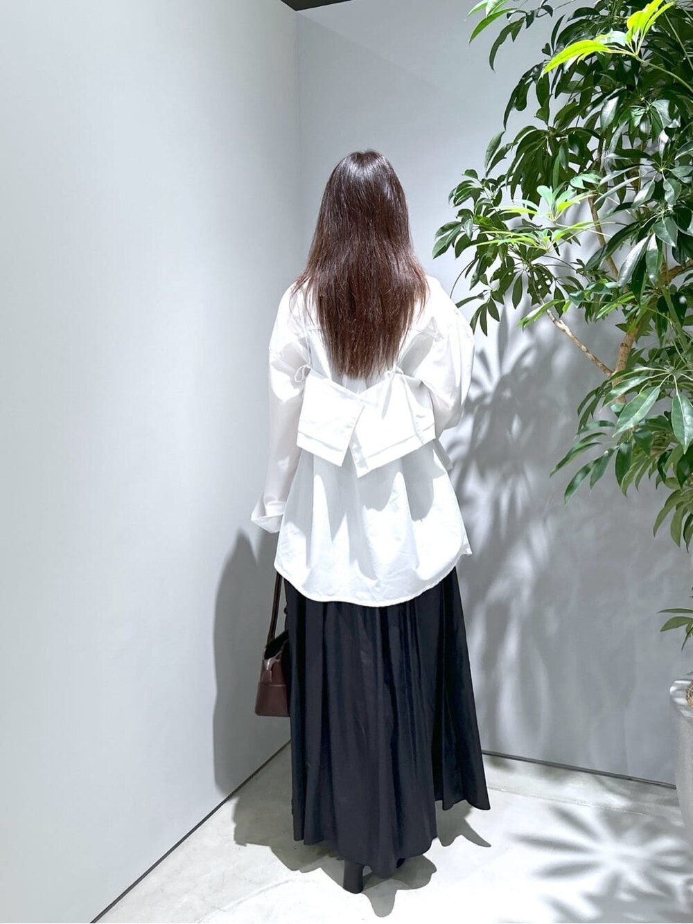 ホワイト系のシャツ/ブラウス、ブラック系のスカート、ブラウン系のショルダーバッグを着用したレディースの秋コーディネートの6枚目の写真