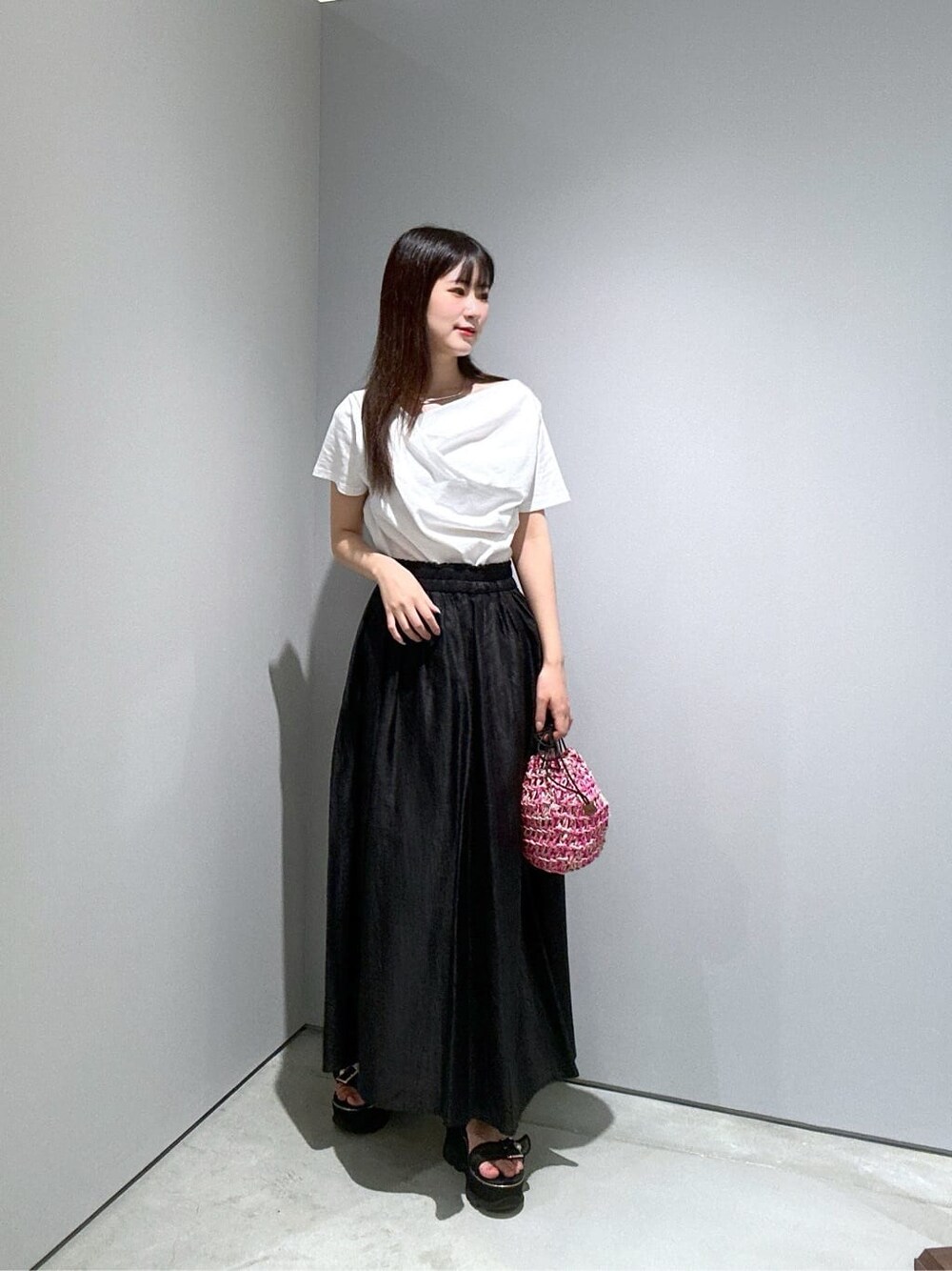ホワイト系のTシャツ/カットソー、ブラック系のスカート、ピンク系のハンドバッグを着用したレディースの夏コーディネートの2枚目の写真