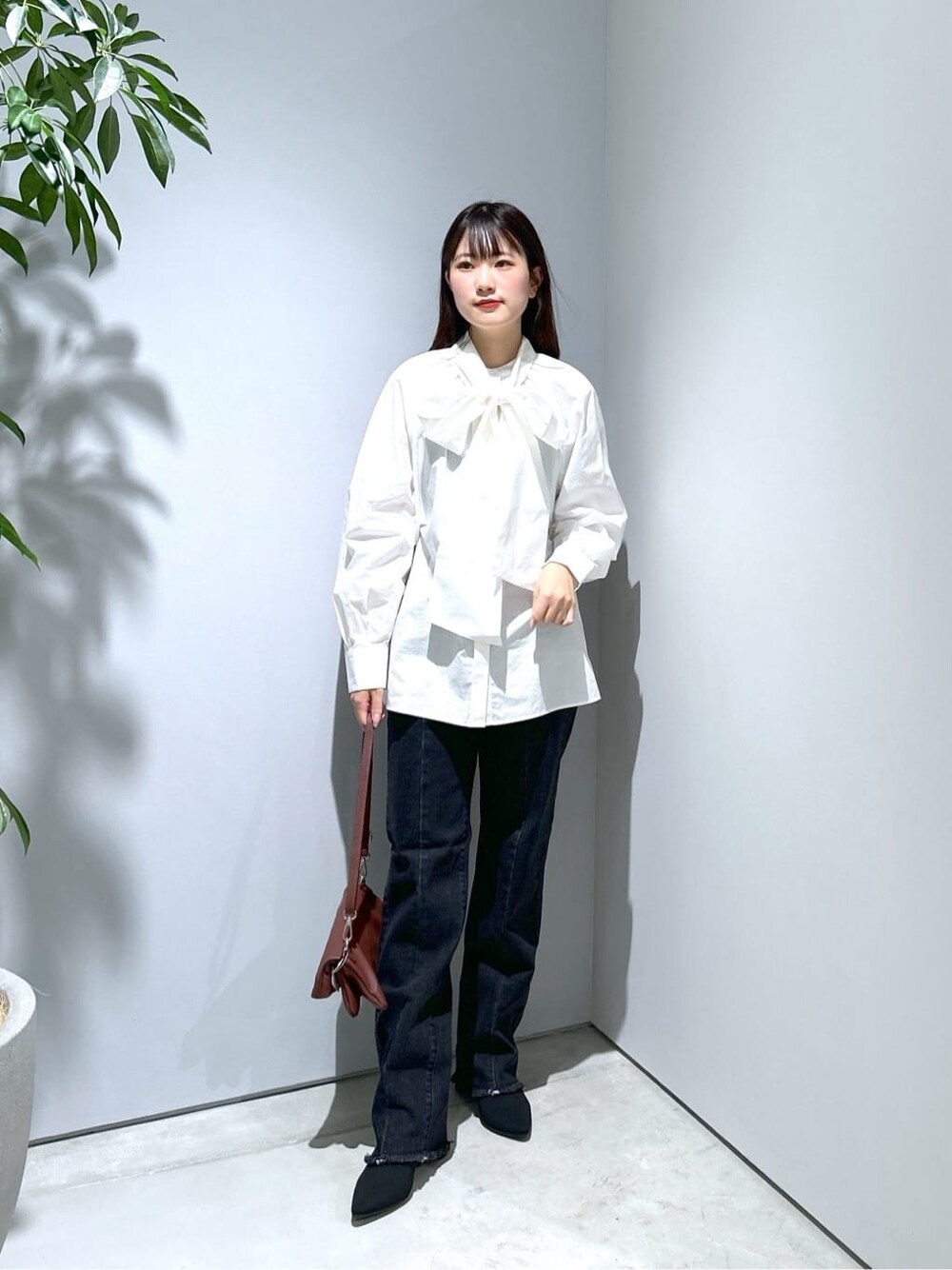 ホワイト系のシャツ/ブラウス、グレー系のデニムパンツ、ブラウン系のショルダーバッグを着用したレディースの秋コーディネートの3枚目の写真