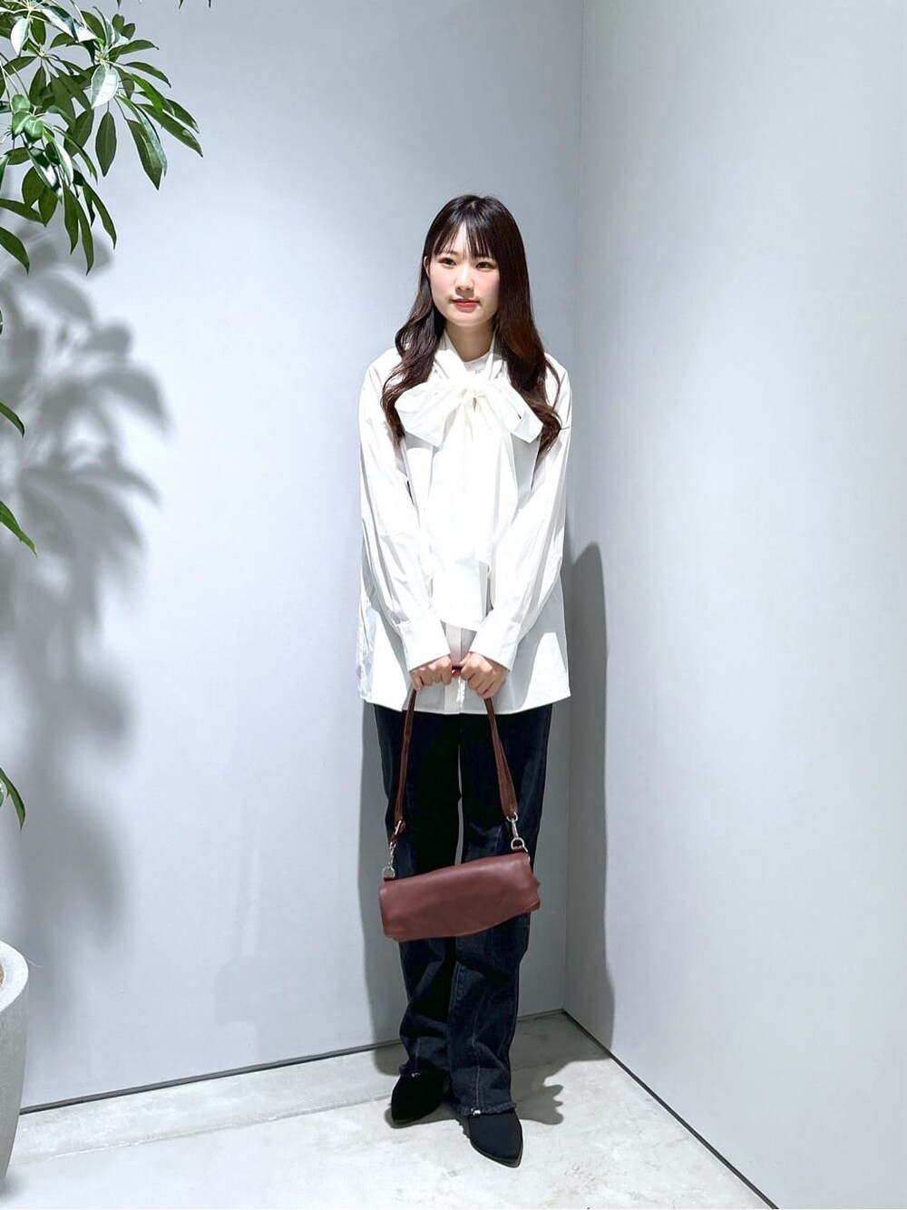 ホワイト系のシャツ/ブラウス、グレー系のデニムパンツ、ブラウン系のショルダーバッグを着用したレディースの秋コーディネートの2枚目の写真