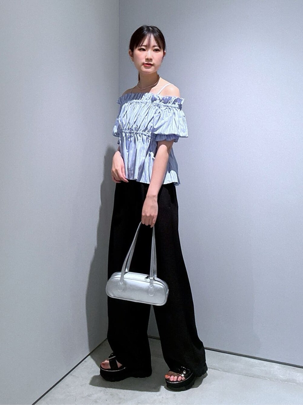 ブルー系のシャツ/ブラウス、ブラック系のその他パンツ、シルバー系のハンドバッグを着用したレディースの夏コーディネートの2枚目の写真