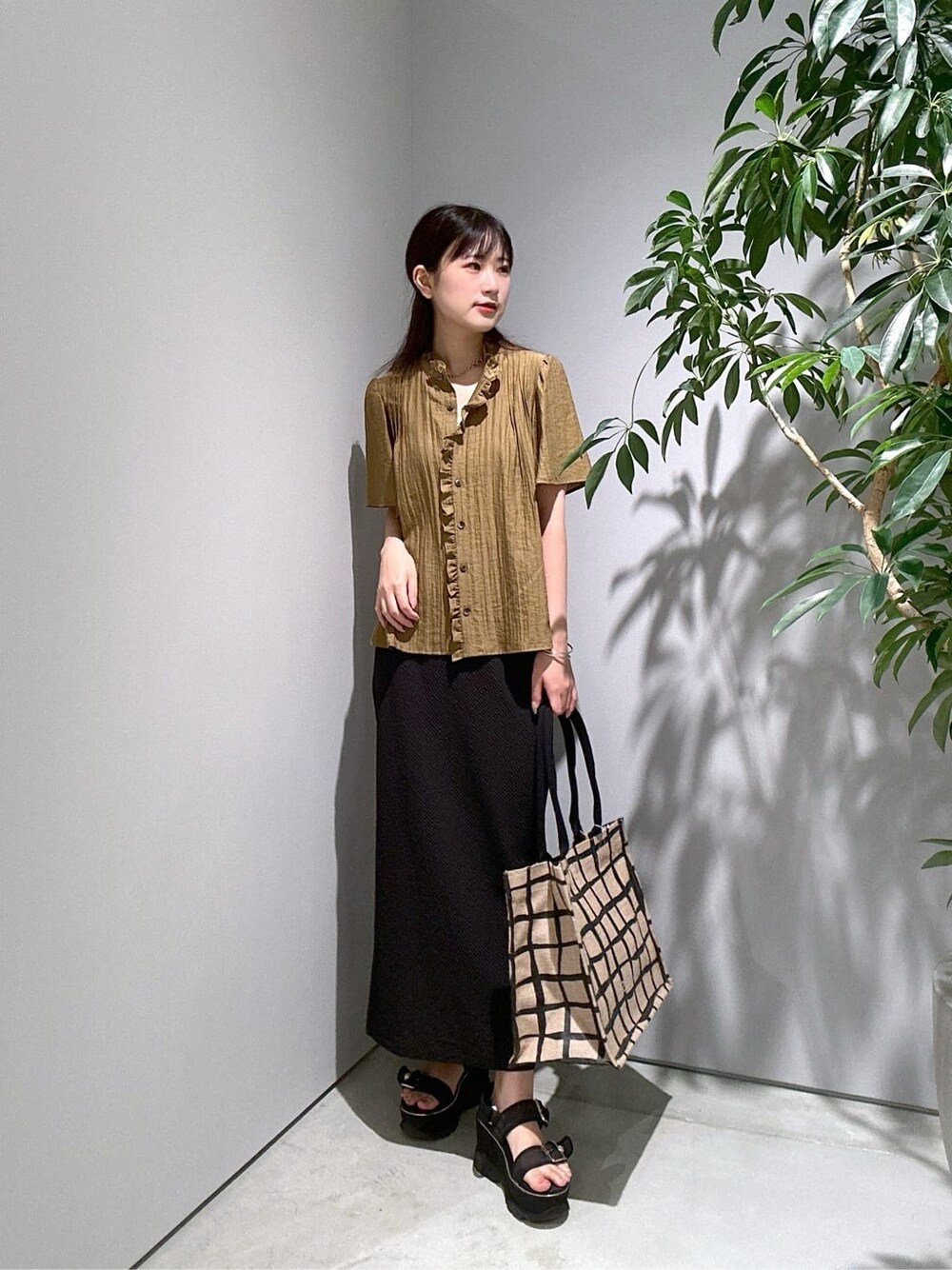 グリーン系のシャツ/ブラウス、ブラック系のスカート、ベージュ系のトートバッグを着用したレディースの夏コーディネートの3枚目の写真