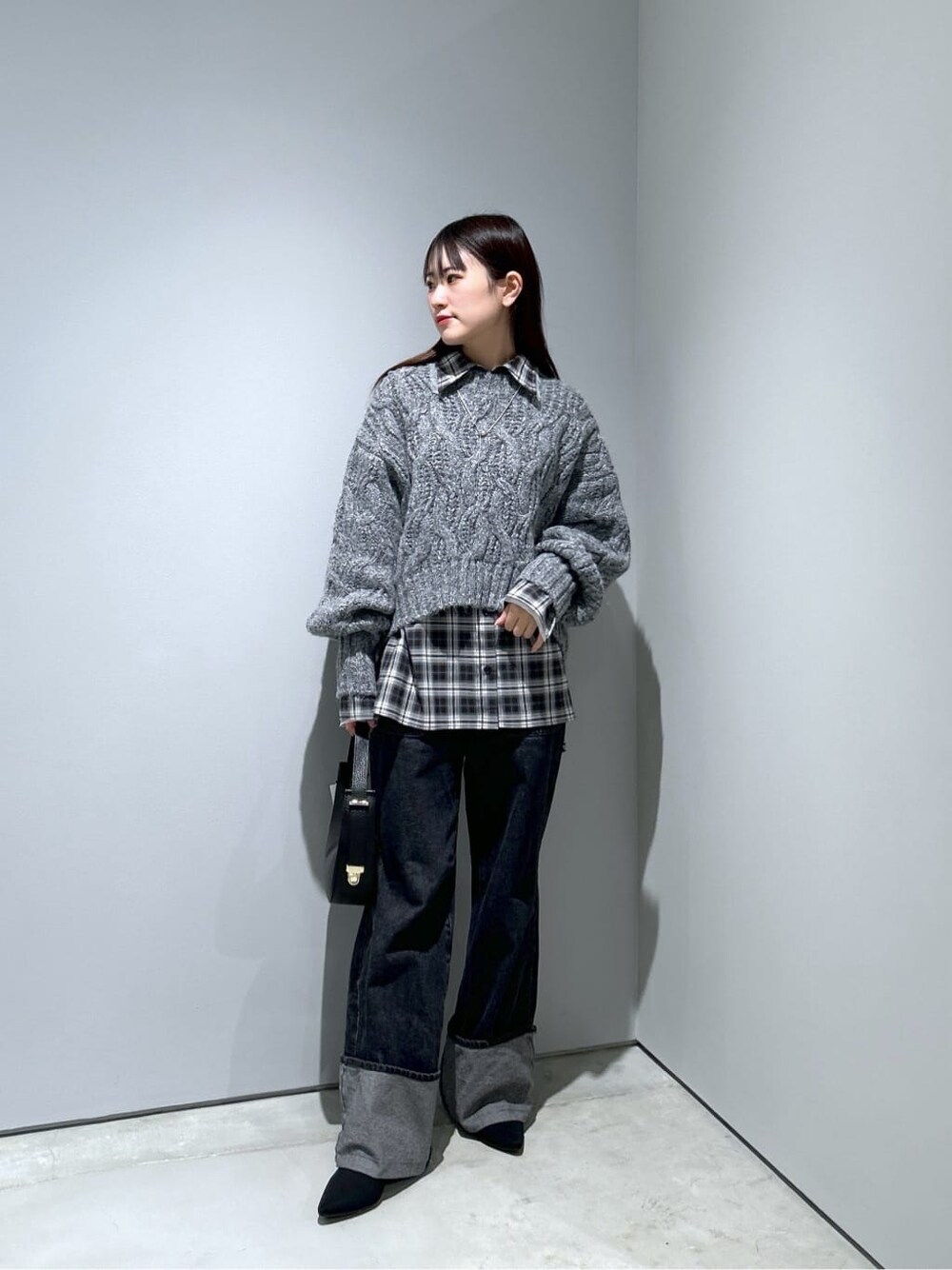 グレー系のニット/セーター、ブラック系のシャツ/ブラウス、グレー系のデニムパンツを着用したレディースの冬コーディネートの2枚目の写真