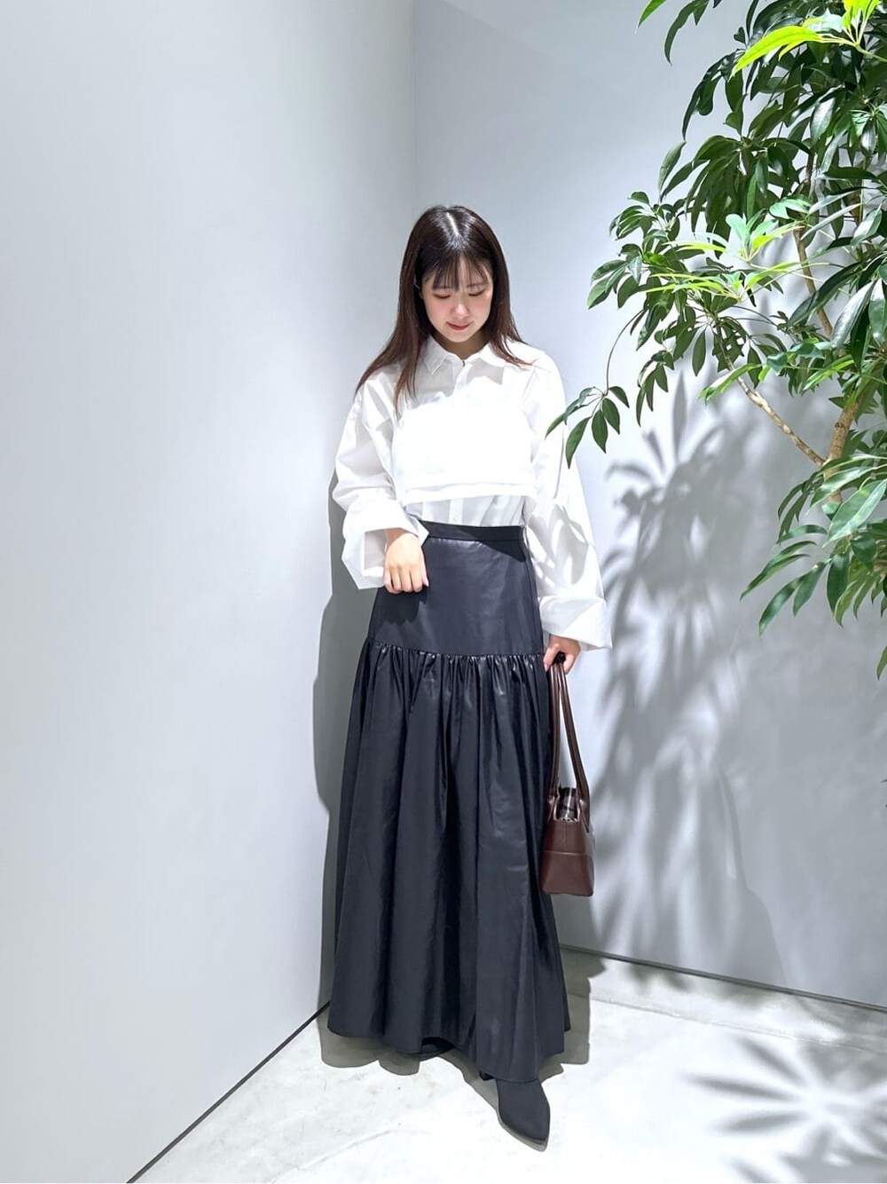ホワイト系のシャツ/ブラウス、ブラック系のスカート、ブラウン系のショルダーバッグを着用したレディースの秋コーディネートの4枚目の写真