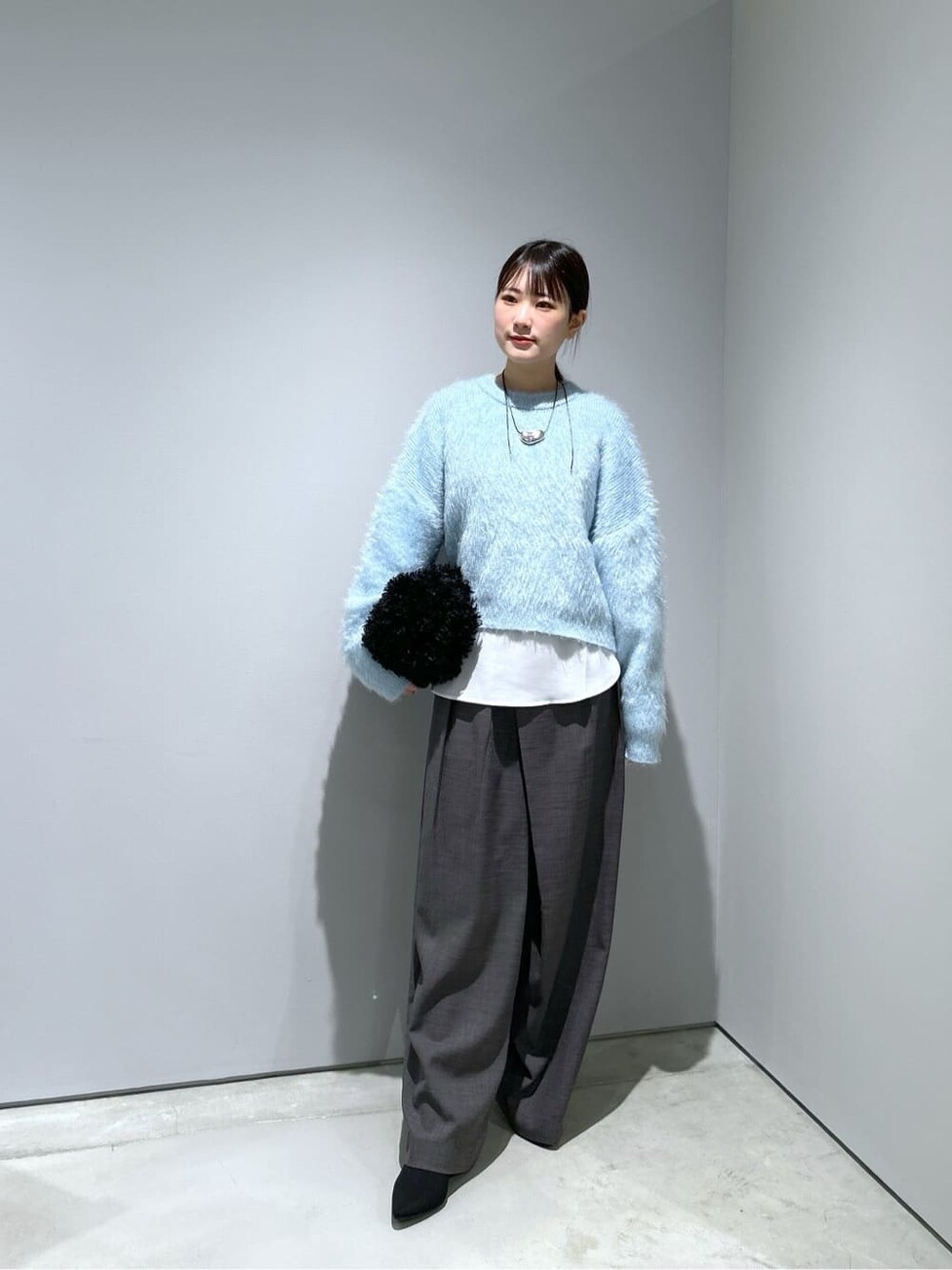 ブルー系のニット/セーター、ホワイト系のシャツ/ブラウス、グレー系のその他パンツを着用したレディースの秋コーディネートの2枚目の写真
