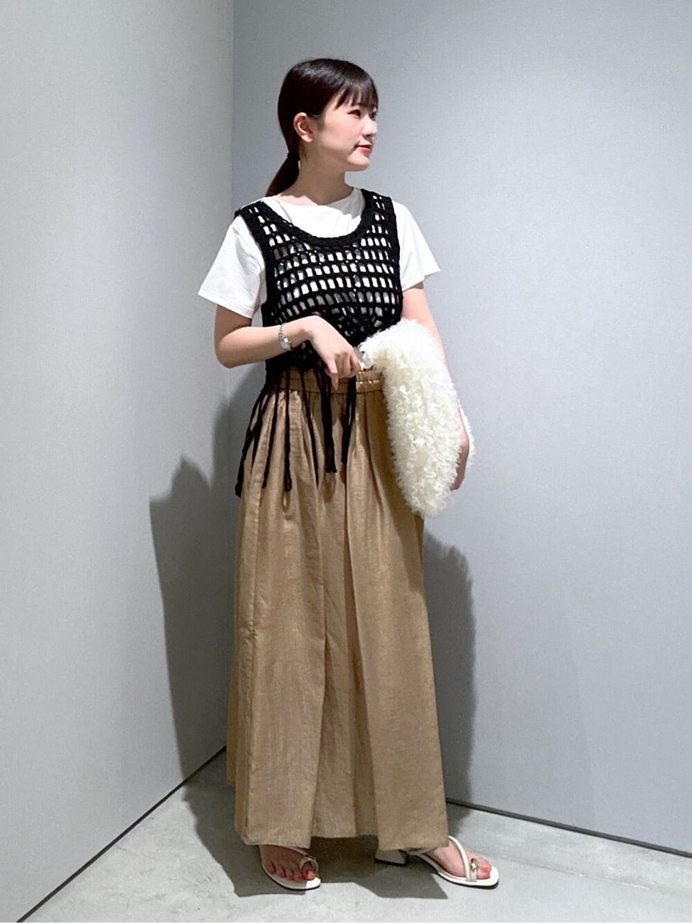 ホワイト系のTシャツ/カットソー、イエロー系のスカート、ホワイト系のサンダルを着用したレディースの夏コーディネートの2枚目の写真