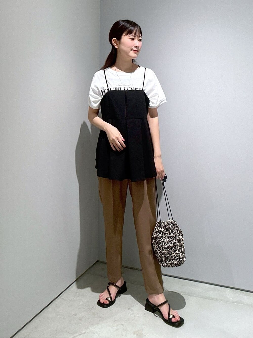 ブラック系のタンクトップ、イエロー系のその他パンツ、ブラック系のハンドバッグを着用したレディースの夏コーディネートの2枚目の写真