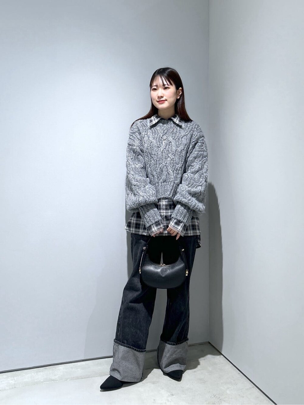 グレー系のニット/セーター、ブラック系のシャツ/ブラウス、グレー系のデニムパンツを着用したレディースの冬コーディネートの3枚目の写真
