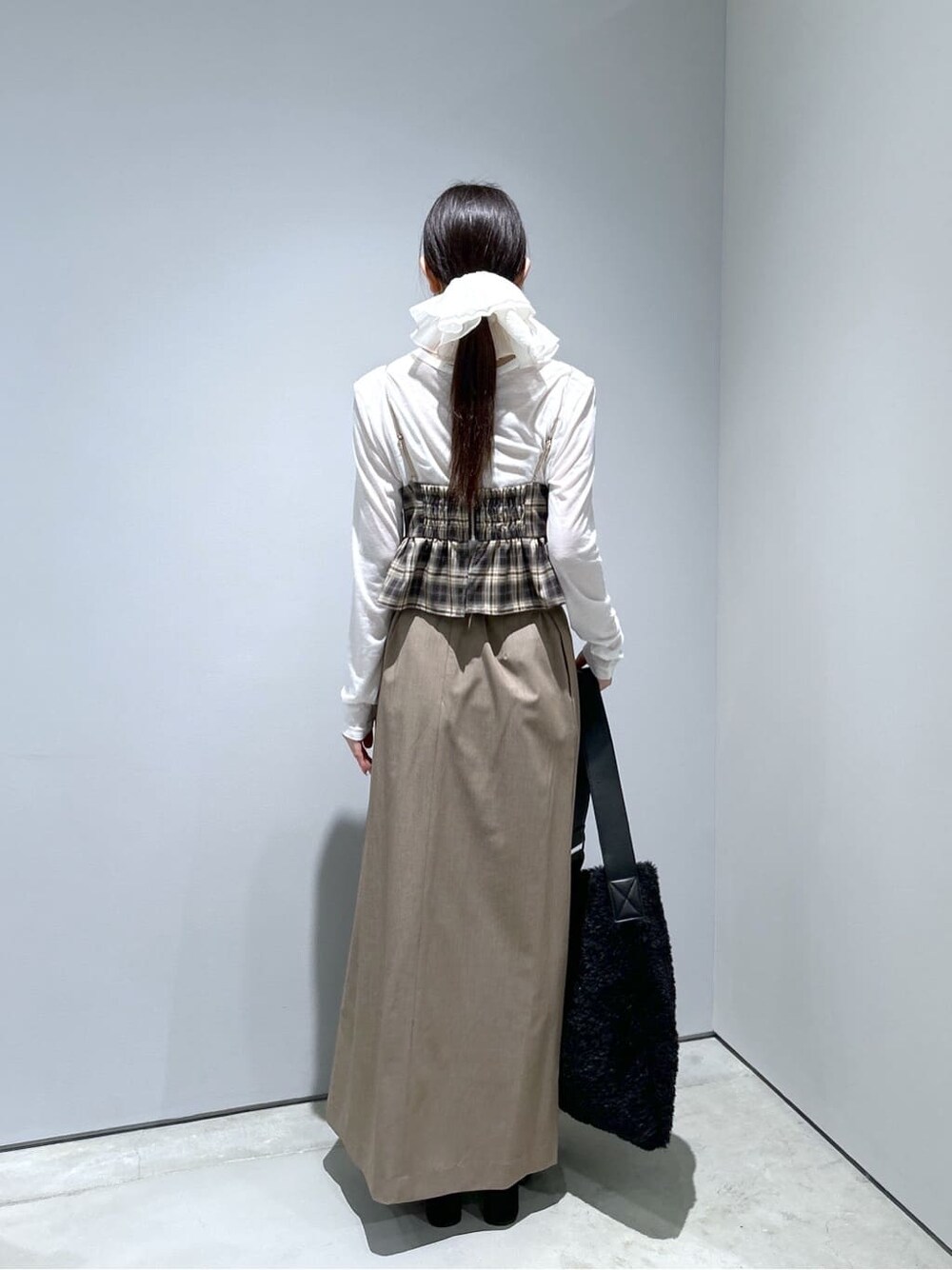ベージュ系のタンクトップ、ホワイト系のTシャツ/カットソー、ベージュ系のスカートを着用したレディースの冬コーディネートの5枚目の写真