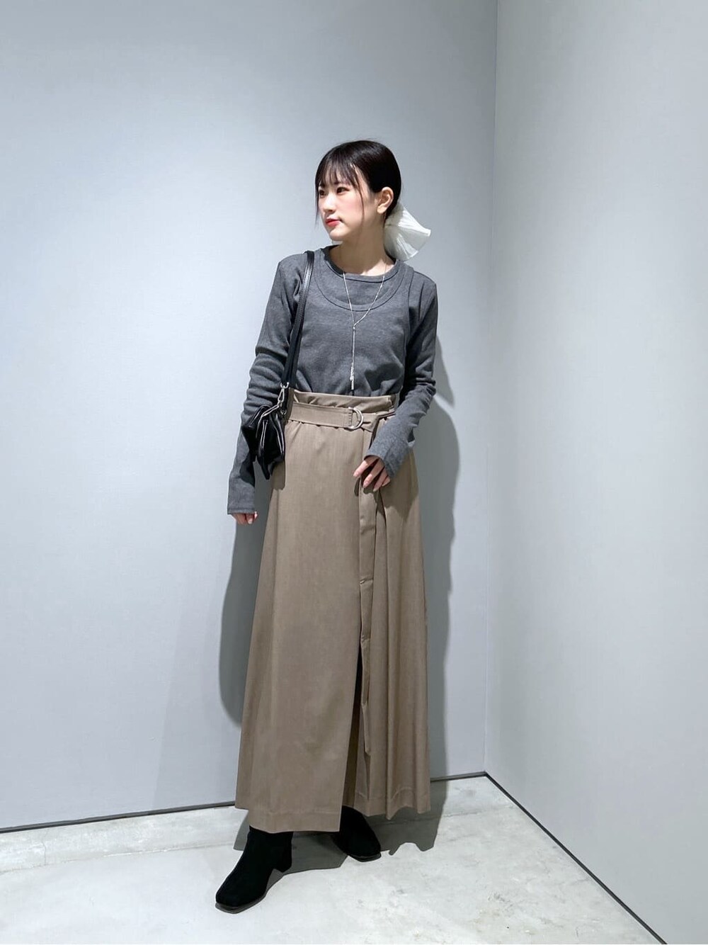 グレー系のTシャツ/カットソー、ベージュ系のスカート、ブラック系のショルダーバッグを着用したレディースの冬コーディネートの2枚目の写真
