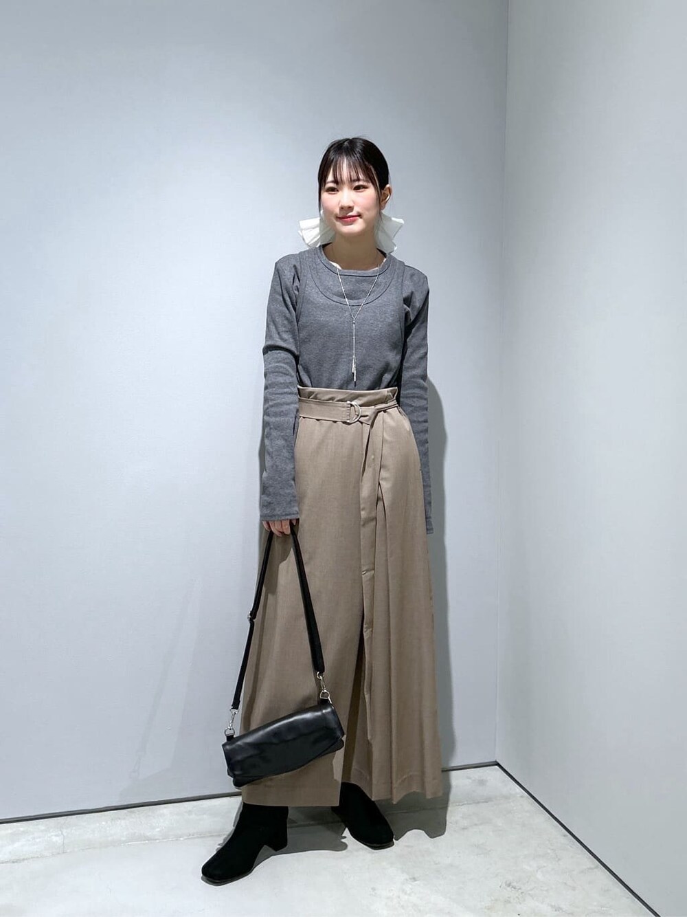 グレー系のTシャツ/カットソー、ベージュ系のスカート、ブラック系のショルダーバッグを着用したレディースの冬コーディネートの3枚目の写真