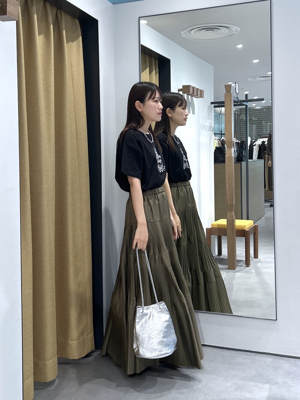 ブラック系のTシャツ/カットソー、グリーン系のスカート、シルバー系のハンドバッグを着用したレディースの夏コーディネートの5枚目の写真
